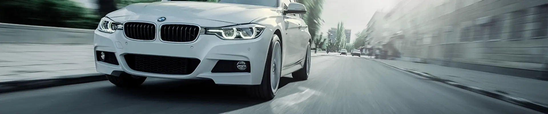 Weißer BMW fährt durch den Stadtverkehr.